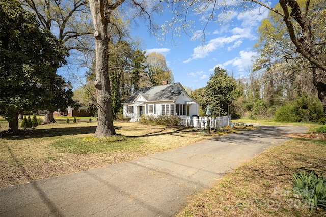 view of front of house featuring a front yard, driveway, and a chimney