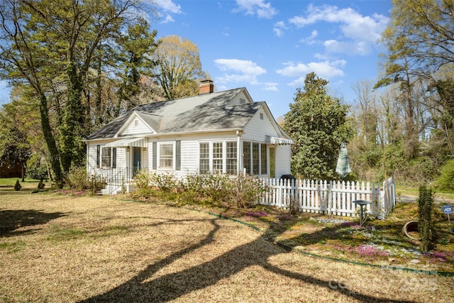rear view of house featuring a yard, fence, and a chimney