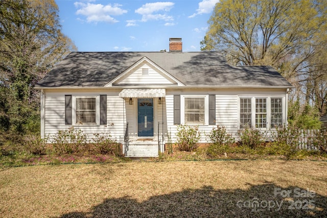 view of front of home with a chimney, a shingled roof, and a front lawn