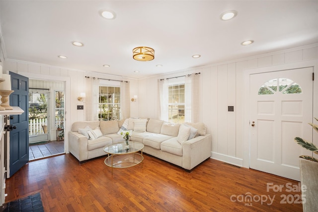 living room with visible vents, wood finished floors, and crown molding