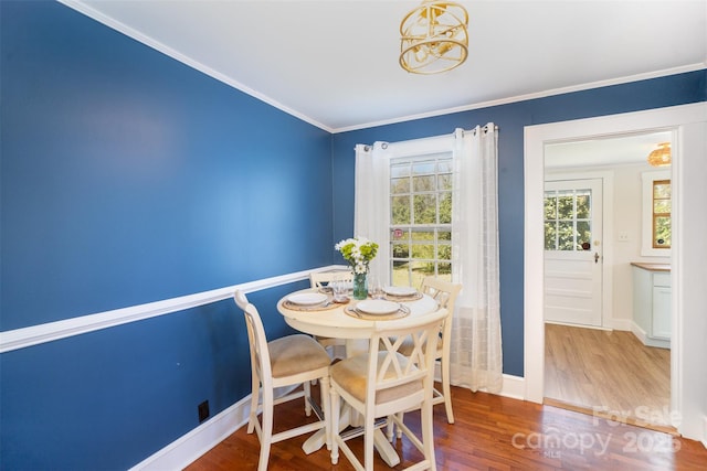 dining space featuring baseboards, wood finished floors, ornamental molding, and an inviting chandelier