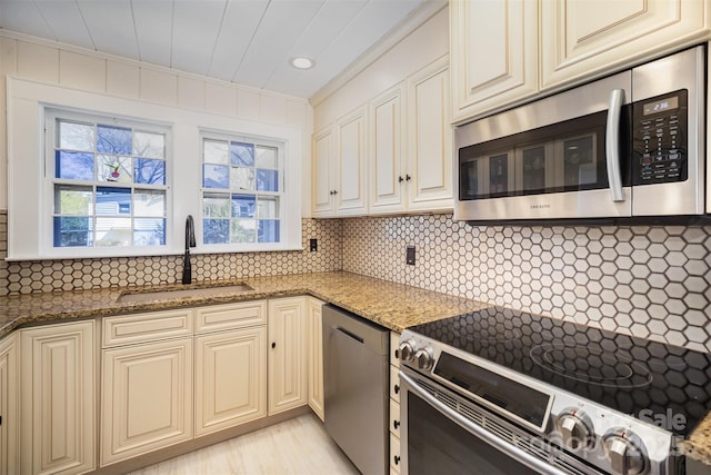 kitchen featuring a sink, crown molding, cream cabinetry, and appliances with stainless steel finishes