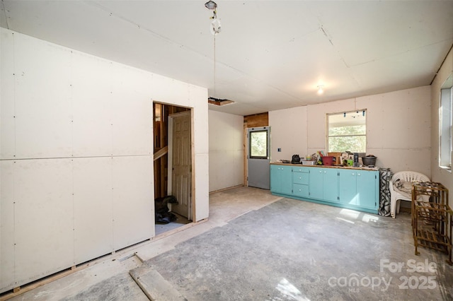 interior space featuring unfinished concrete flooring and blue cabinetry