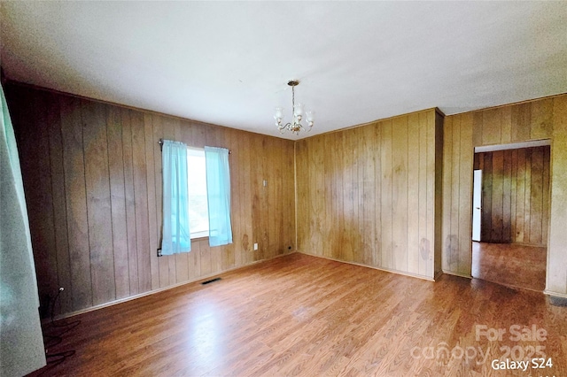 410 Cole Campbell Rd, Taylorsville, NC 28681 - empty room featuring wood walls, wood finished floors, visible vents, and an inviting chandelier