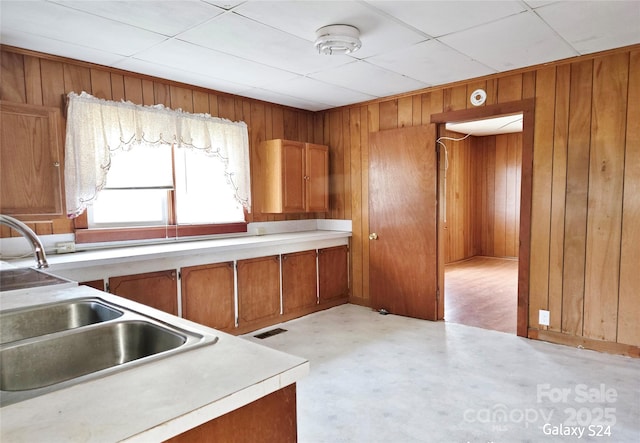 410 Cole Campbell Rd, Taylorsville, NC 28681 - kitchen featuring light countertops, wooden walls, visible vents, a sink, and brown cabinetry