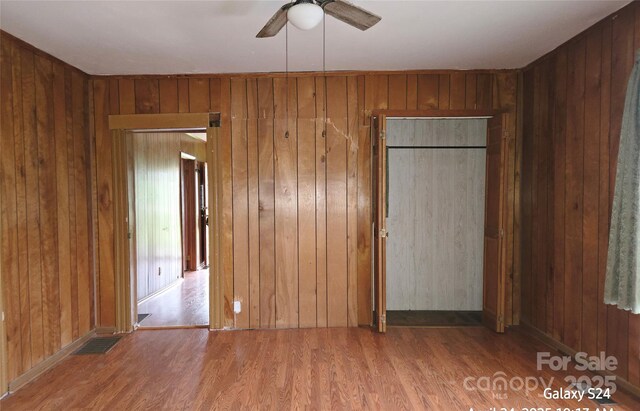 410 Cole Campbell Rd, Taylorsville, NC 28681 - unfurnished bedroom with wooden walls, wood finished floors, visible vents, and a ceiling fan