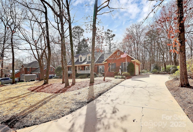 view of front of home featuring concrete driveway, a garage, brick siding, and a residential view