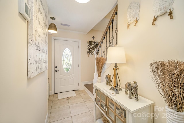 foyer entrance featuring light tile patterned floors, baseboards, visible vents, stairway, and ornamental molding