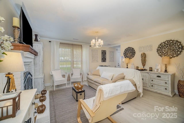 living room featuring a chandelier, crown molding, a fireplace, and light wood-style floors