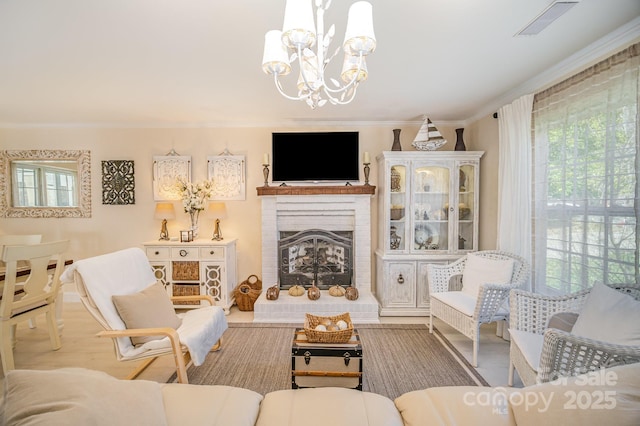 living area featuring a notable chandelier, plenty of natural light, a fireplace, and crown molding