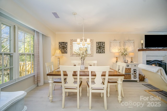 dining area with ornamental molding, light wood-type flooring, a chandelier, and visible vents