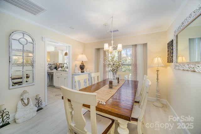 dining room featuring light wood-type flooring, an inviting chandelier, visible vents, and crown molding