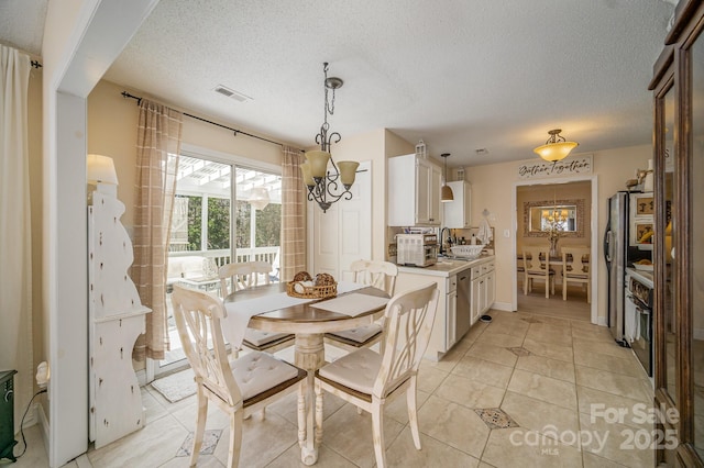 dining area featuring a toaster, visible vents, a textured ceiling, and light tile patterned flooring