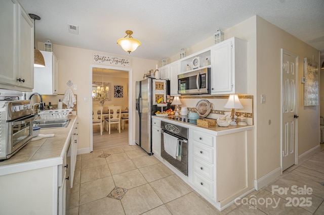 kitchen featuring open shelves, tile counters, white cabinets, a sink, and black appliances