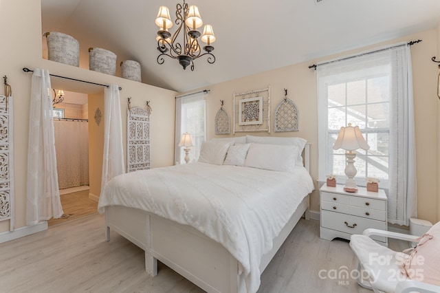 bedroom with multiple windows, an inviting chandelier, and light wood-style floors