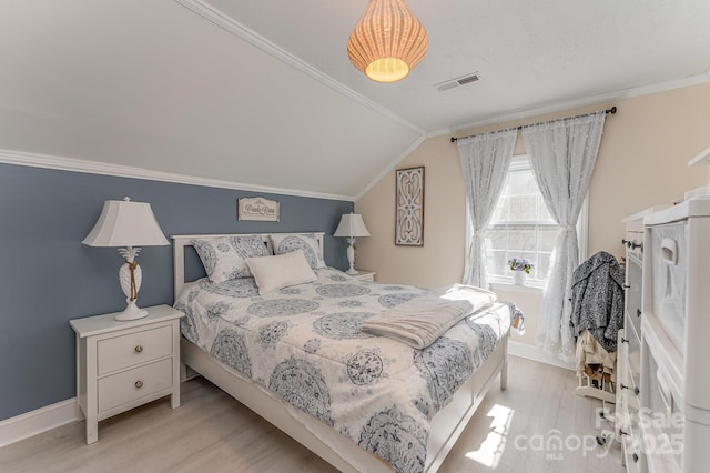 bedroom featuring lofted ceiling, wood finished floors, visible vents, baseboards, and ornamental molding