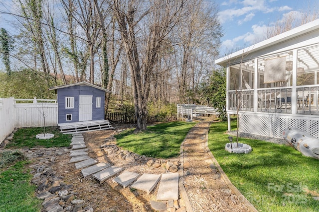 view of yard featuring a storage shed, an outdoor structure, a fenced backyard, and a sunroom