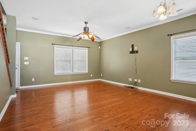 empty room with wood finished floors, baseboards, ornamental molding, and ceiling fan with notable chandelier