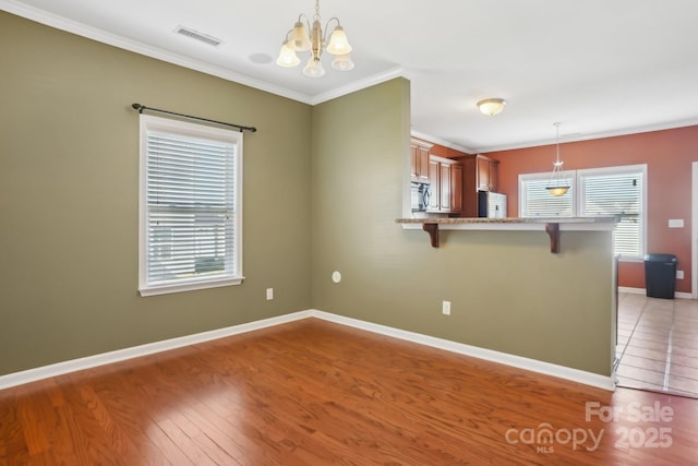 kitchen featuring a wealth of natural light, a kitchen breakfast bar, a notable chandelier, and ornamental molding