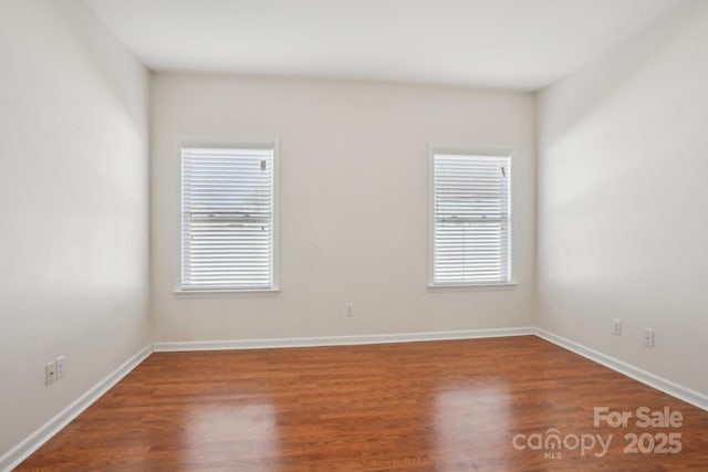 spare room featuring baseboards, plenty of natural light, and wood finished floors