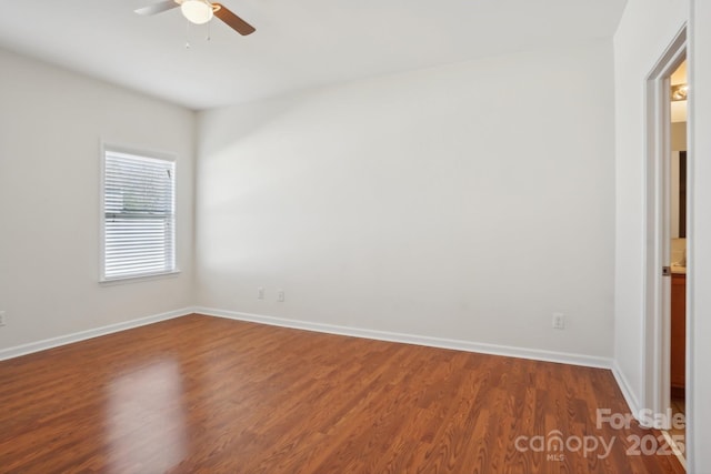 empty room featuring baseboards, ceiling fan, and dark wood finished floors