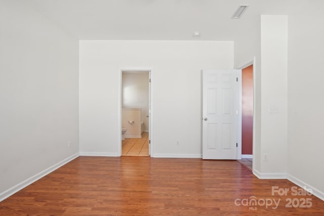 unfurnished bedroom featuring visible vents, wood finished floors, and baseboards