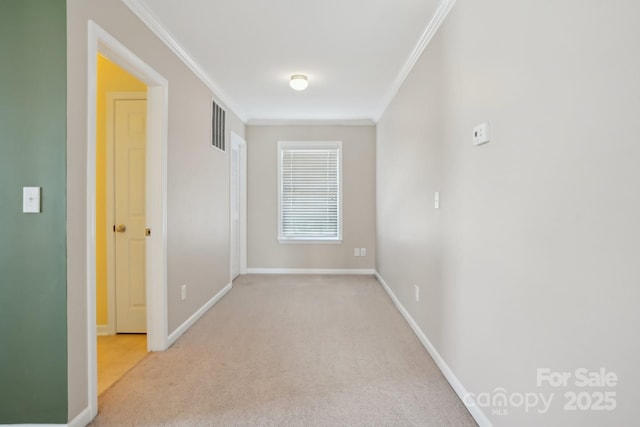 spare room featuring crown molding, baseboards, and carpet floors