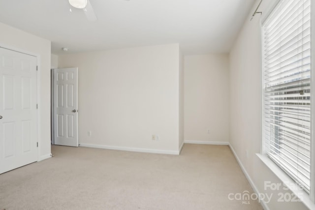 unfurnished bedroom with baseboards, multiple windows, and light colored carpet