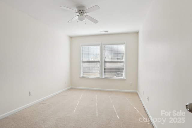 carpeted spare room featuring visible vents, a ceiling fan, and baseboards