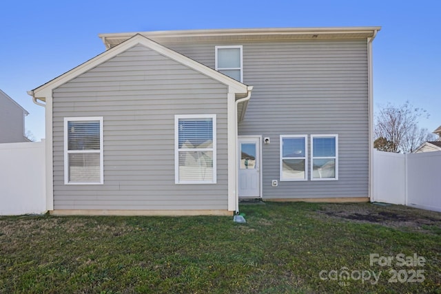 rear view of property featuring a yard and fence