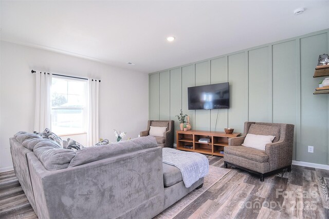 living area with a decorative wall, recessed lighting, wood finished floors, and baseboards