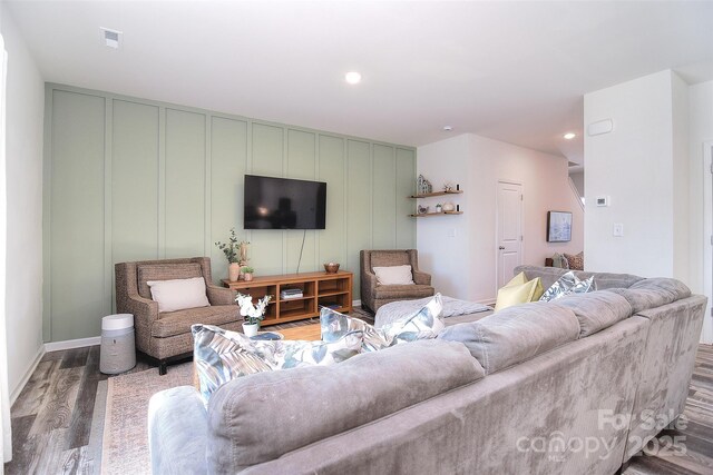 living area with a decorative wall, recessed lighting, wood finished floors, and visible vents