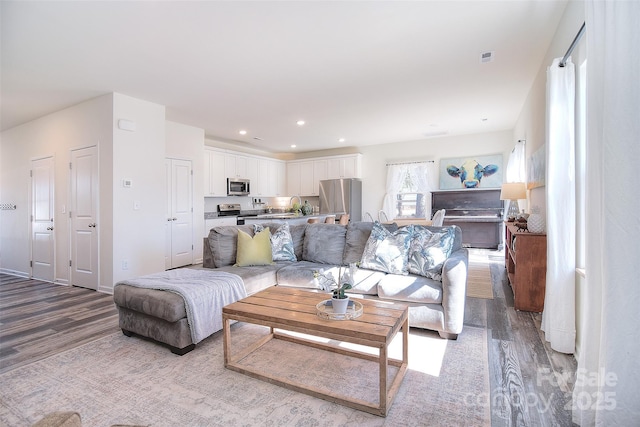 living room with recessed lighting, baseboards, and light wood-style floors