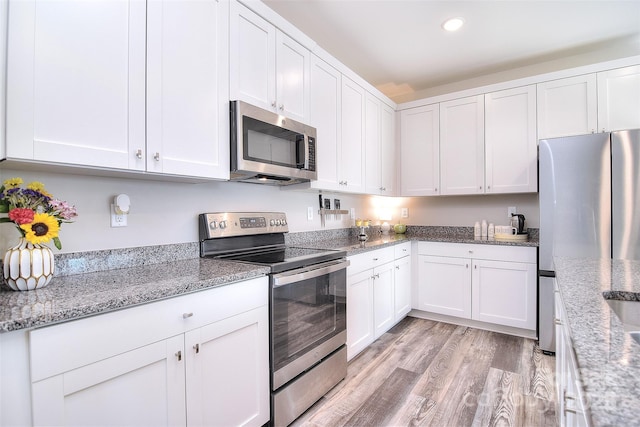 kitchen with recessed lighting, light wood-type flooring, appliances with stainless steel finishes, and white cabinets