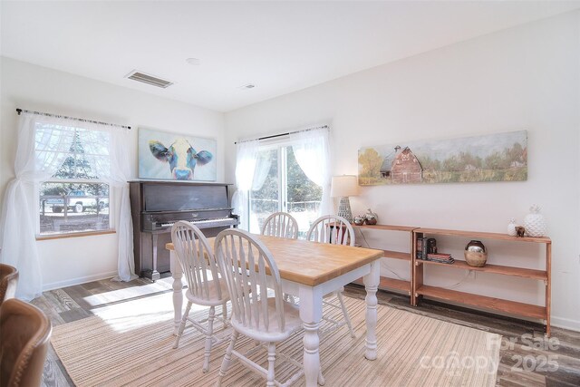 dining area with wood finished floors, visible vents, and baseboards