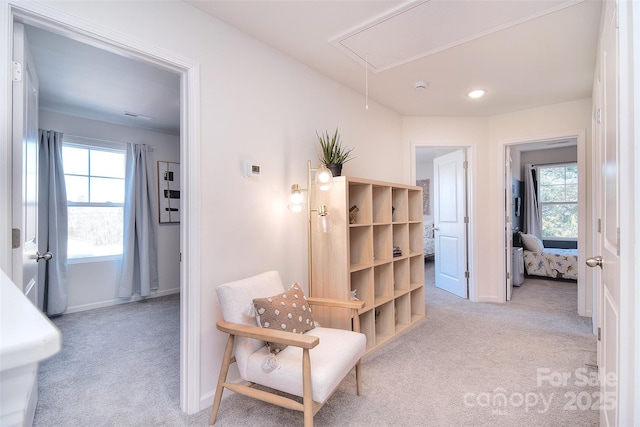 corridor with baseboards, light colored carpet, and attic access