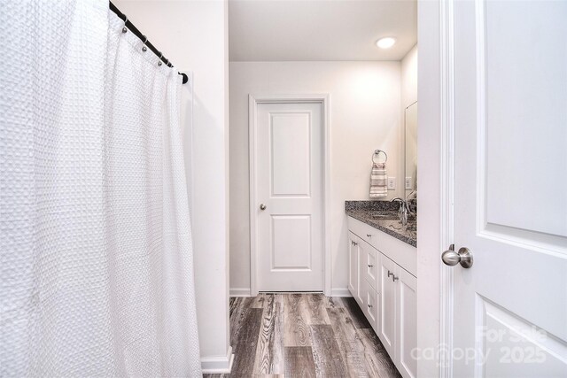 full bath featuring baseboards, wood finished floors, and vanity