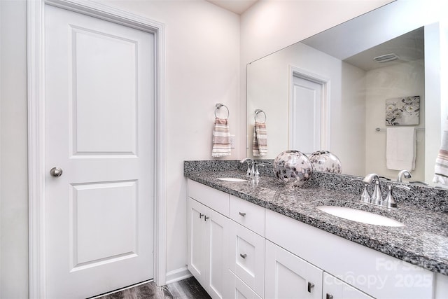 bathroom featuring double vanity, visible vents, wood finished floors, and a sink