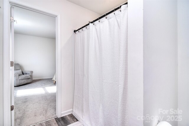 bathroom with a shower with curtain, baseboards, and wood finished floors