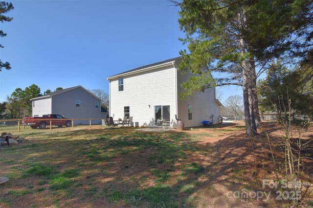 rear view of property featuring a patio area, fence, and a lawn