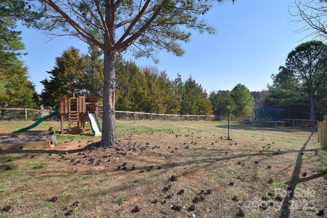 view of yard with a playground, a trampoline, and fence