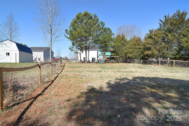 view of yard with an outbuilding, a playground, and fence