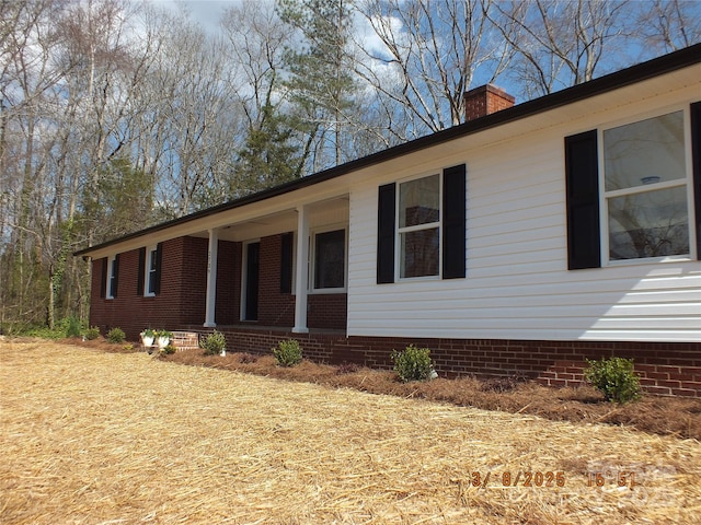 view of side of home featuring covered porch and a chimney