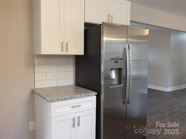 kitchen featuring tasteful backsplash, stainless steel fridge with ice dispenser, white cabinetry, light stone countertops, and baseboards