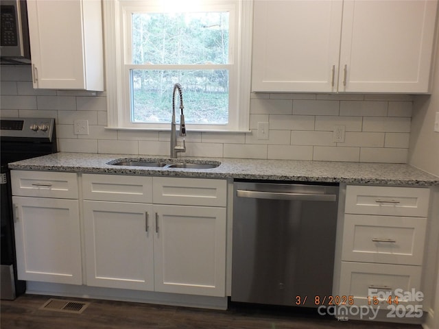 kitchen with stainless steel appliances, white cabinets, a sink, and visible vents