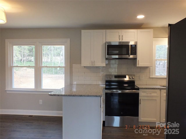 kitchen featuring appliances with stainless steel finishes, backsplash, white cabinetry, and light stone countertops