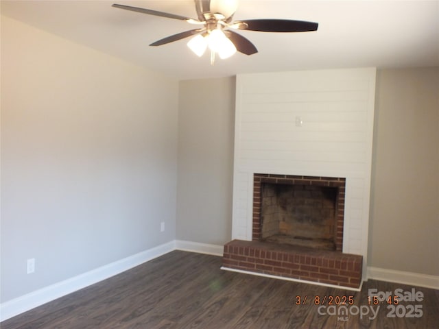 unfurnished living room with ceiling fan, a fireplace, baseboards, and dark wood-style flooring