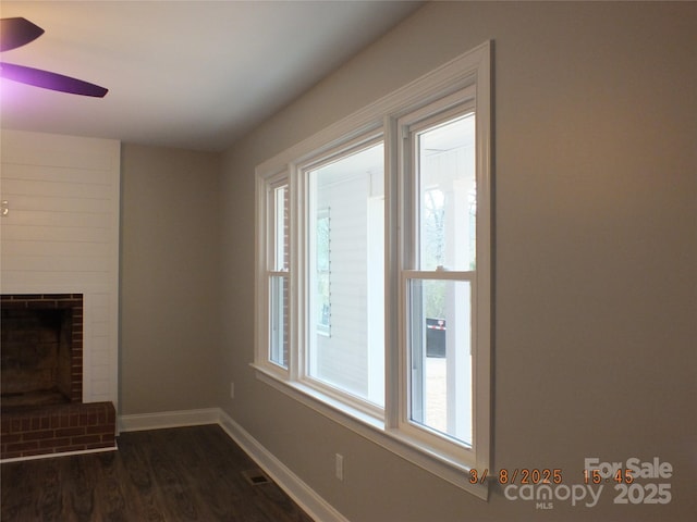 unfurnished living room with ceiling fan, dark wood-type flooring, a fireplace, and baseboards