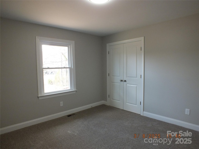 unfurnished bedroom with a closet, carpet, visible vents, and baseboards