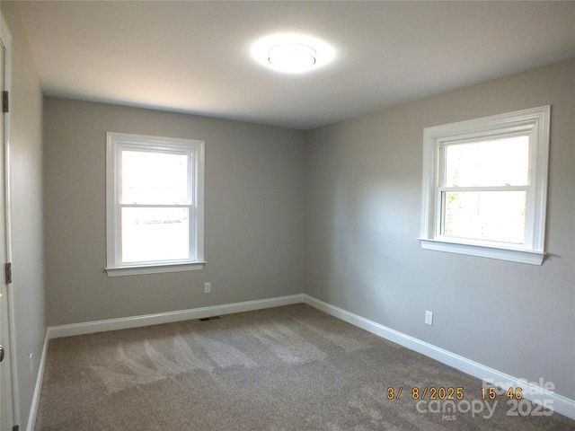 carpeted spare room featuring plenty of natural light and baseboards